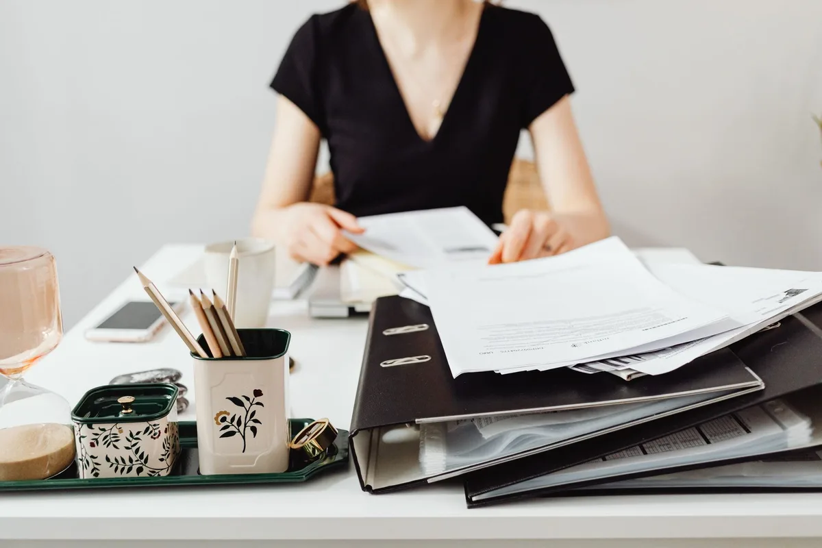 Mains triant des documents et dossiers dans des catégories étiquetées sur un bureau