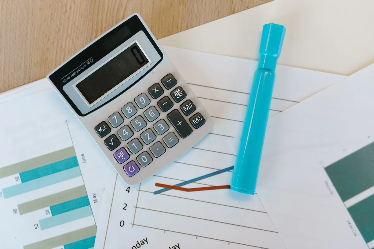 Bureau avec calculatrice, feuilles de calcul et documents budgétaires marketing, symbole du calcul du ratio d'efficacité