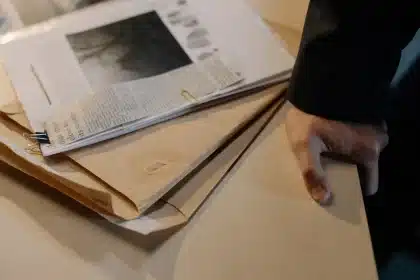 Personne examinant des documents financiers avec une loupe pour détecter les arnaque