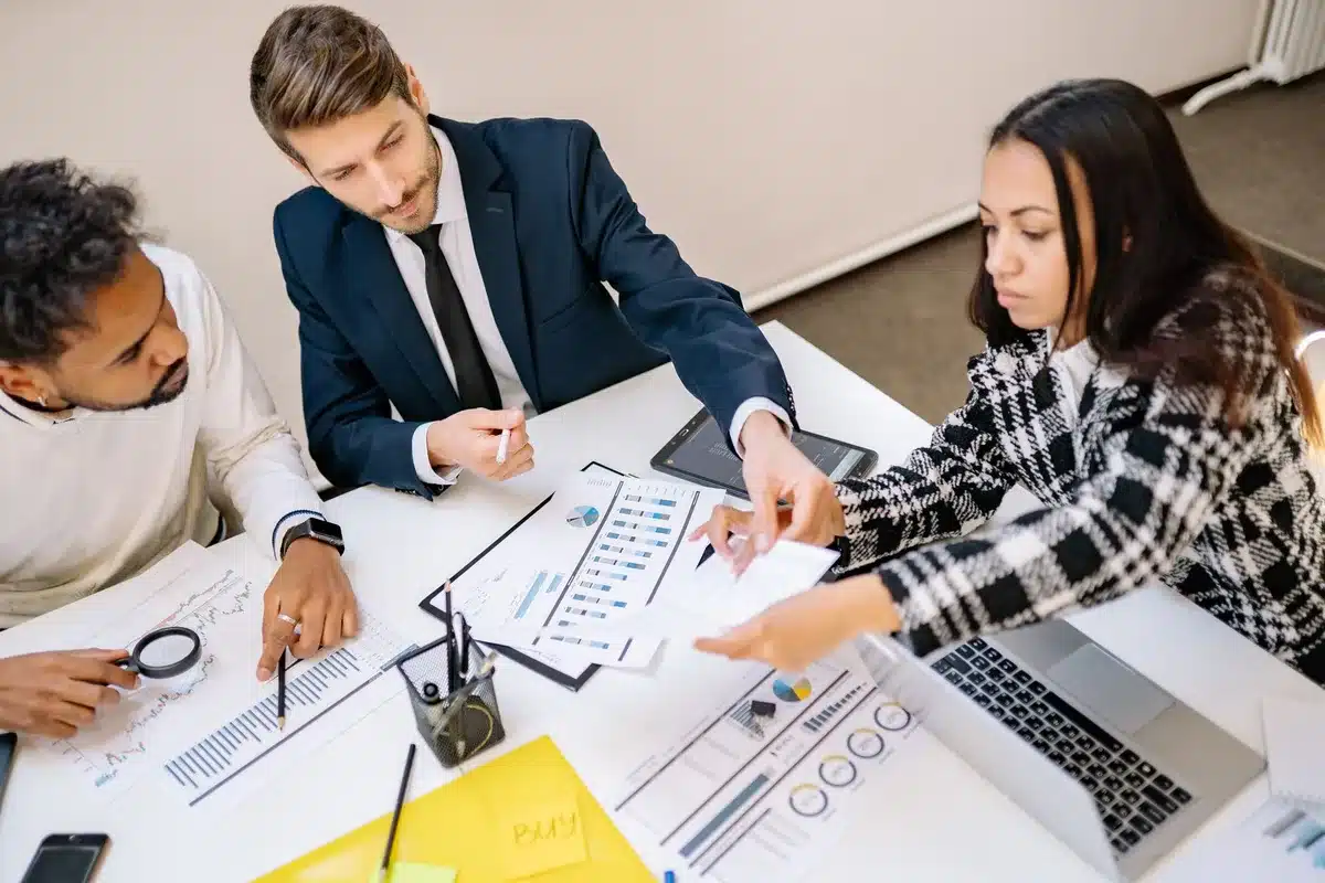 Équipe marketing discutant autour d'une table avec ordinateurs portables et graphiques