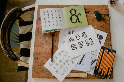 Mains de graphiste comparant des échantillons de polices et des caractères typographiques sur un plan de travail