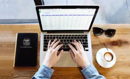 Rédacteur web comparant les tarifs et fonctionnalités de plusieurs plateformes sur son ordinateur