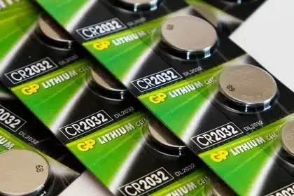 Mains gantées préparant des piles AA près d'une batterie de téléphone sur une table