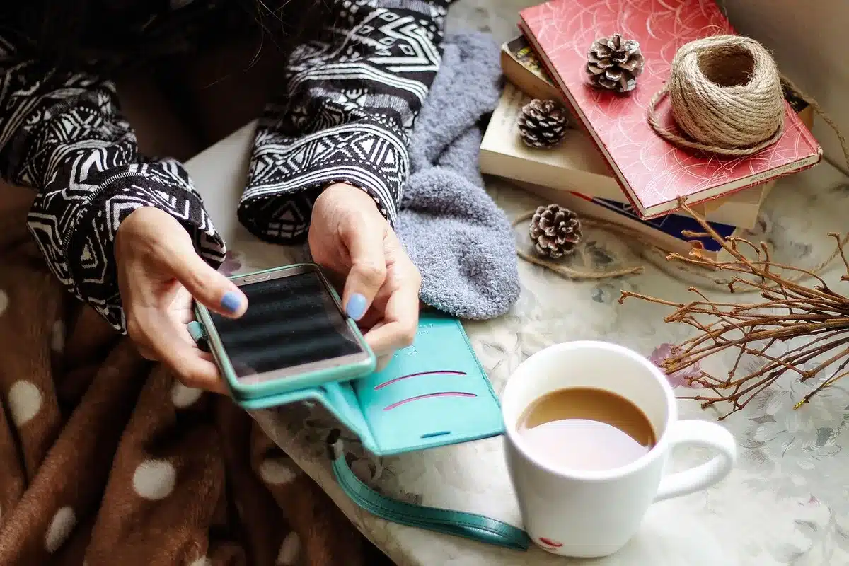 Mains tenant un smartphone et un tiroir SIM sur une table près d'une fenêtre en plein jour