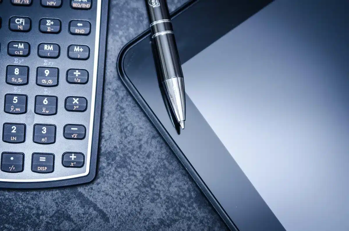 Main avec calculatrice et documents de frais d'investissement sur une table