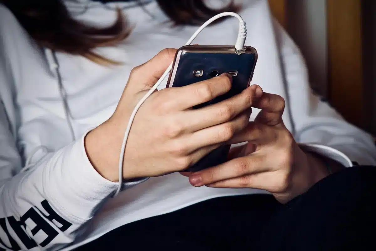 Smartphone tenu près d’un téléviseur dans un salon lumineux montrant la mise en miroir