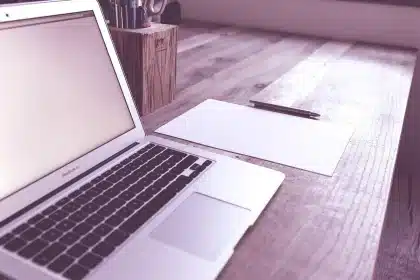 Bureau à domicile en plein jour avec ordinateur affichant un wireframe de site, carnet et tasse de café