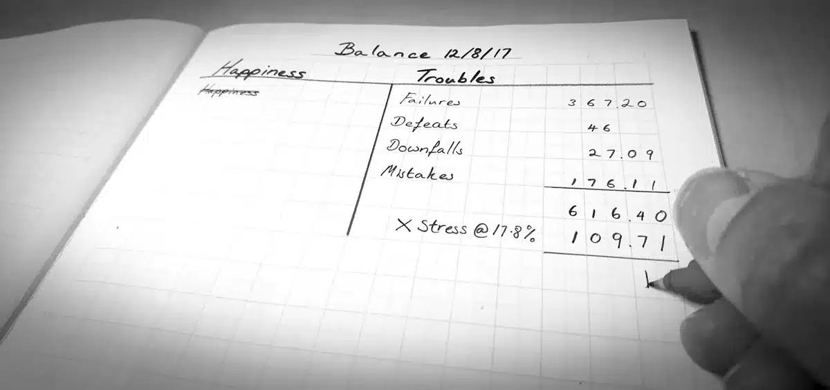 Mains tenant une liste de courses et un stylo sur une table de cuisine en plein jour