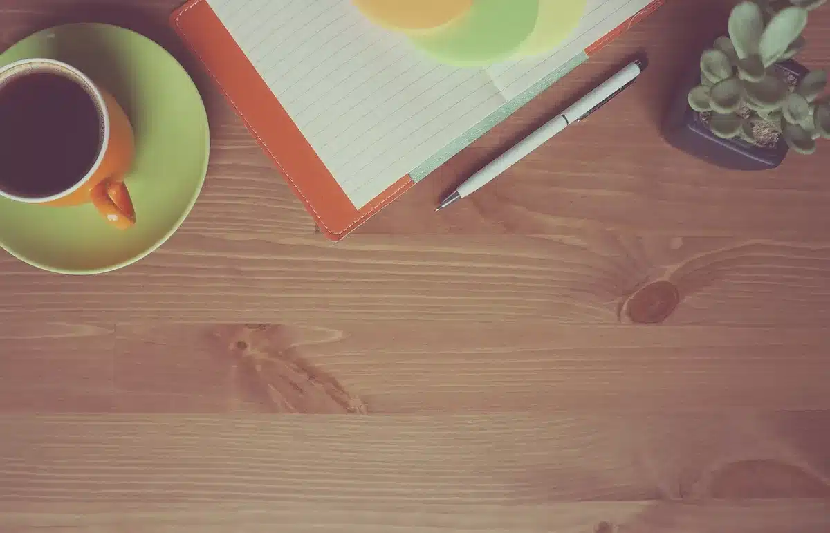 Bureau en lumière du jour avec ordinateur portable et main sur clavier, illustrant la rédaction d'un email de bienvenue