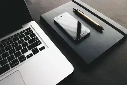 Bureau lumineux avec smartphone sur une table et mains anonymes manipulant un câble