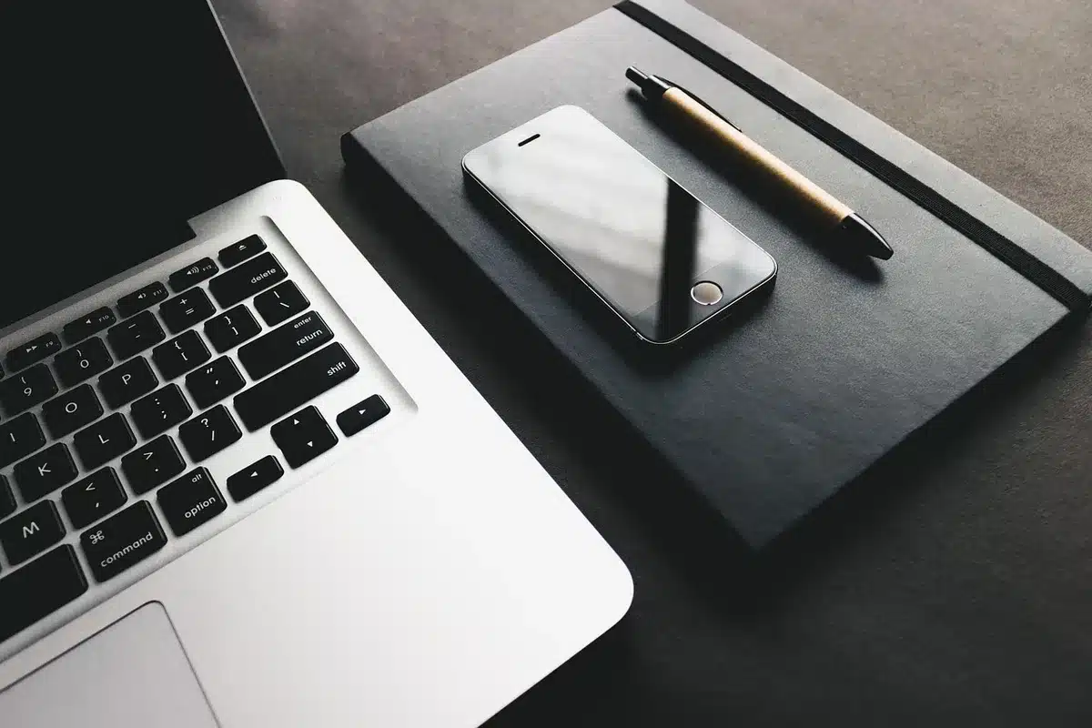 Bureau lumineux avec smartphone sur une table et mains anonymes manipulant un câble