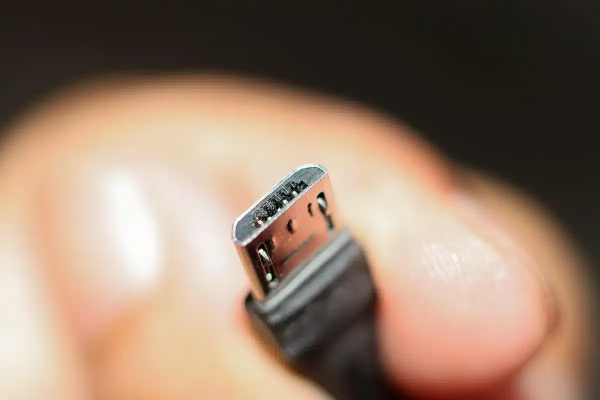 Smartphone connecté via câble USB à un port de voiture, intérieur en journée