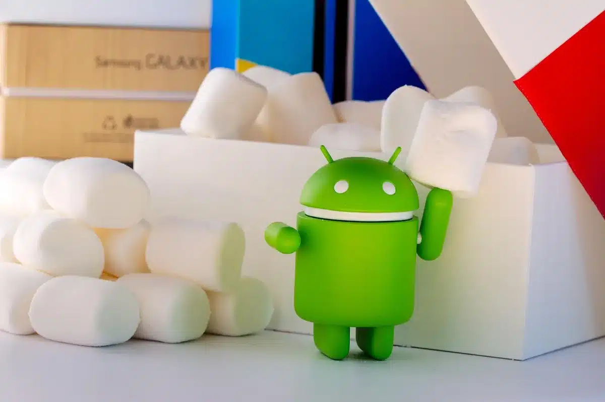 Smartphone Android sur une table près d'une fenêtre montrant les icônes d'applications, mains et écouteurs à côté