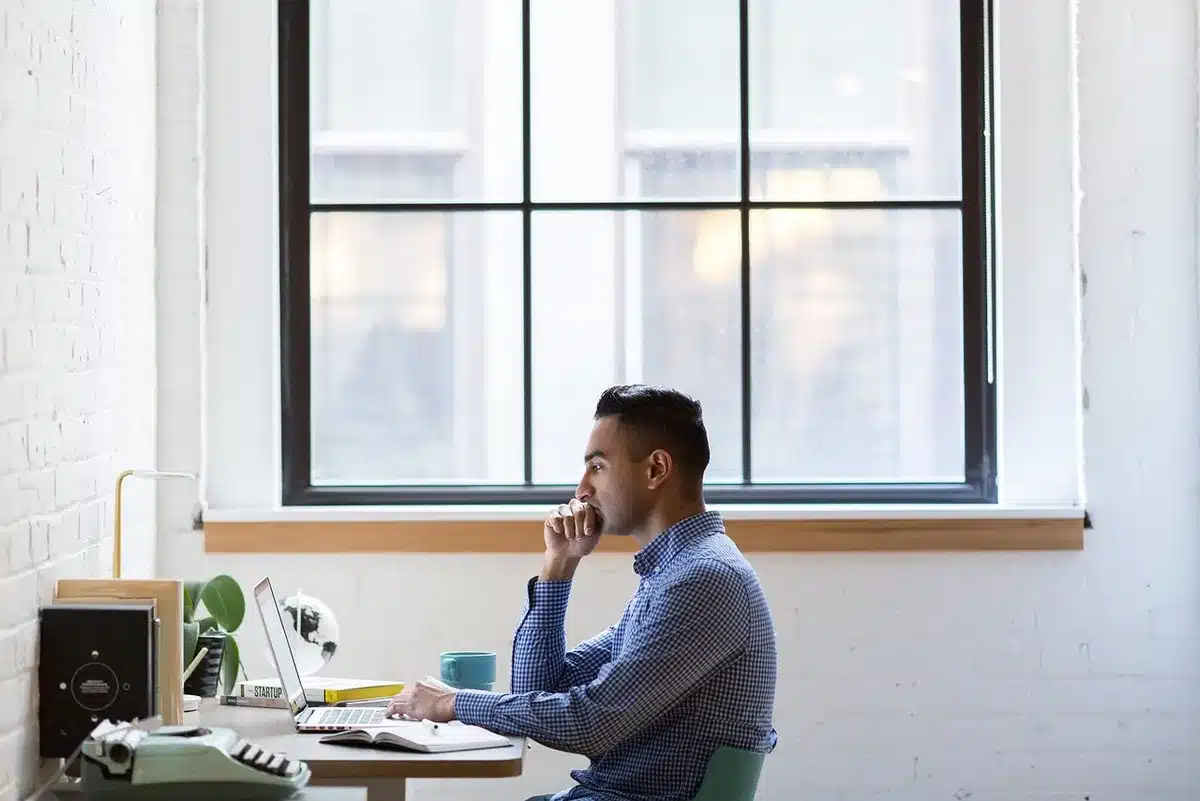 Bureau ensoleillé avec carnet, calculatrice et tasse de café près d'une fenêtre