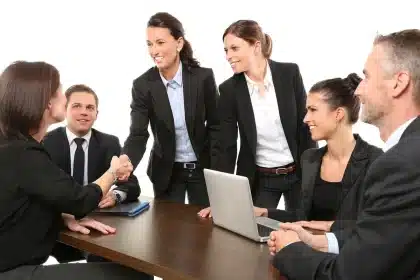 Bureau marketing en plein jour avec briefs imprimés, ordinateur et mains anonymes discutant