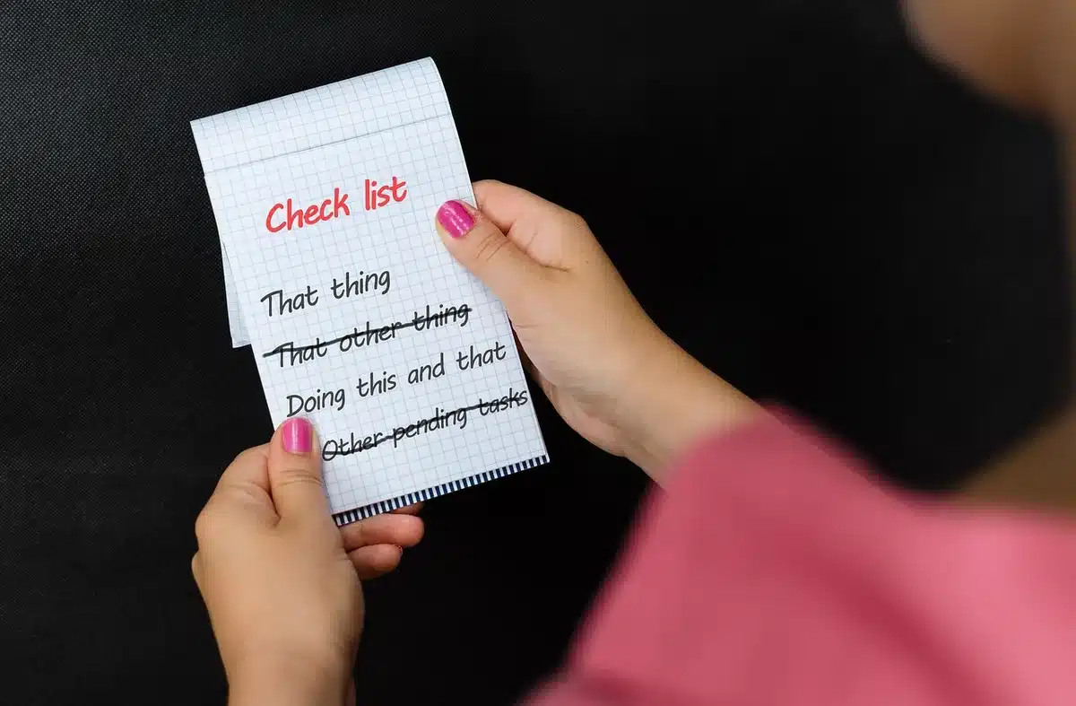 Main tenant une checklist de risques posée sur un bureau lumineux