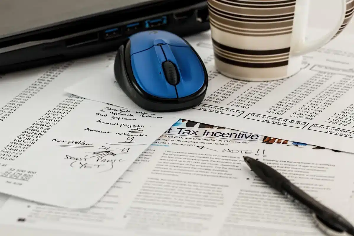 Bureau en journée, mains anonymes sur un document financier et une calculatrice en arrière-plan
