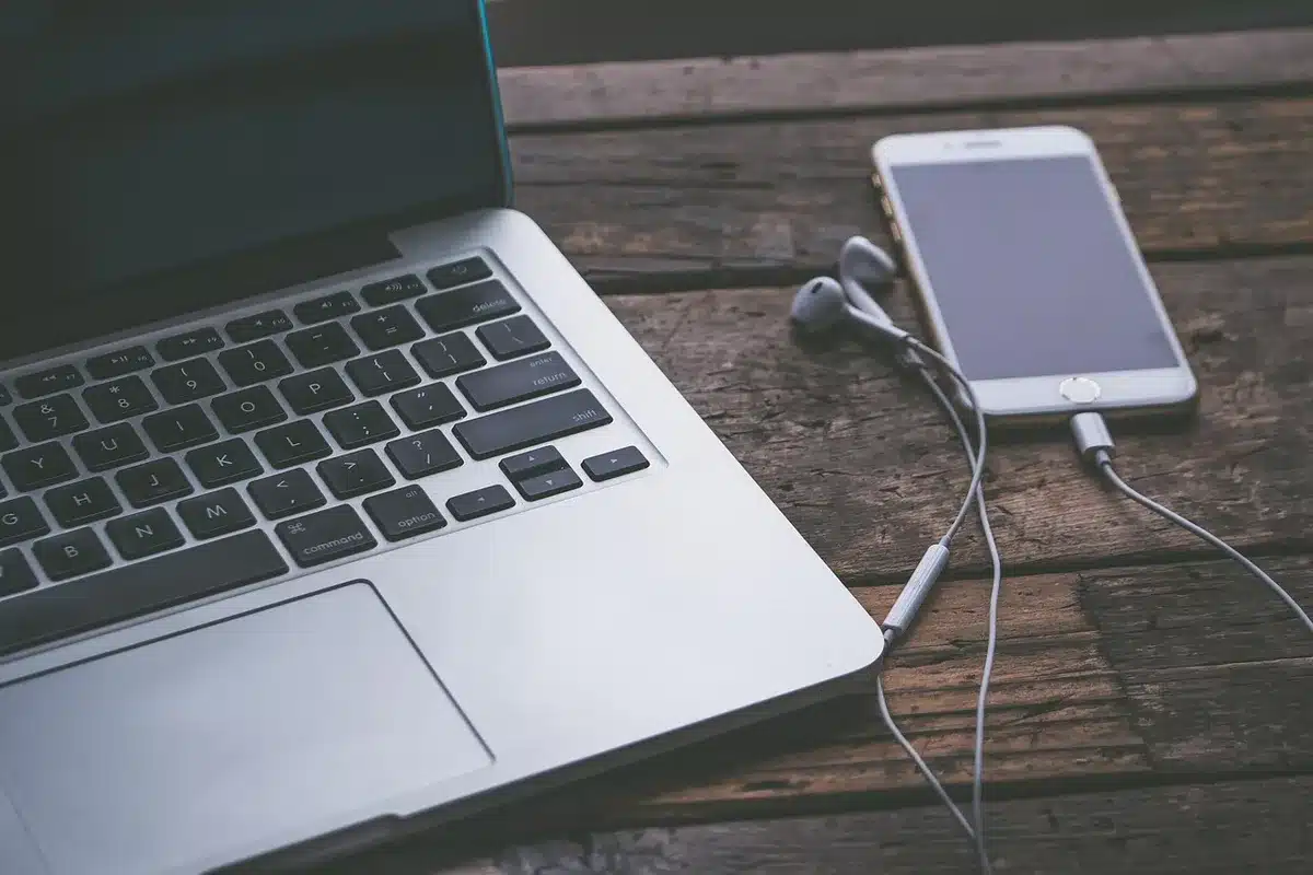 iPhone et MacBook sur un bureau lumineux, icônes d'apps à l'écran